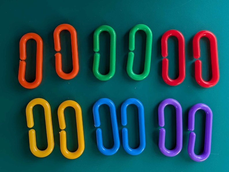 May include: A set of 10 colourful plastic rings, each with a different colour: red, orange, yellow, green, blue, purple, and two shades of blue. The rings are all the same size and shape, and they are arranged in a row.