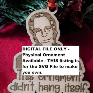 Puede incluir: Adorno navideño de madera con un retrato y la frase "This ornament didn't hang itself." Tiene una cinta roja para colgar. El texto en el adorno dice "DIGITAL FILE ONLY - Physical Ornament Available - THIS listing is for the SVG File to make you own."