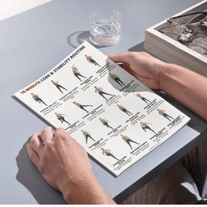 K&ouml;nnte beinhalten: Eine Person h&auml;lt eine gedruckte Trainingsroutine mit dem Titel "16-Minute Core & Stability Routine". Die Routine umfasst illustrierte &Uuml;bungen mit Anweisungen. Ein Glas Wasser und ein Tablett mit Brille sind ebenfalls sichtbar.