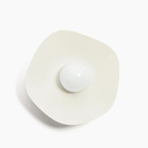 May include: A white ceramic wall sconce with a round, white light bulb in the center.