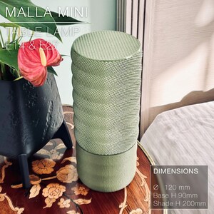 May include: A green table lamp with a textured cylindrical shade. The lamp is 120 mm in diameter, 90 mm tall at the base, and 200 mm tall at the shade. The lamp is labeled "MALLA MINI TABLE LAMP E14 & E27".