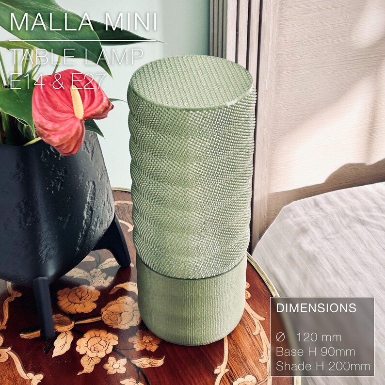 May include: A green table lamp with a textured cylindrical shade. The lamp is 120 mm in diameter, 90 mm tall at the base, and 200 mm tall at the shade. The lamp is labeled "MALLA MINI TABLE LAMP E14 & E27".