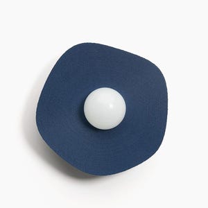 May include: A blue wall sconce with a white round light bulb in the center.