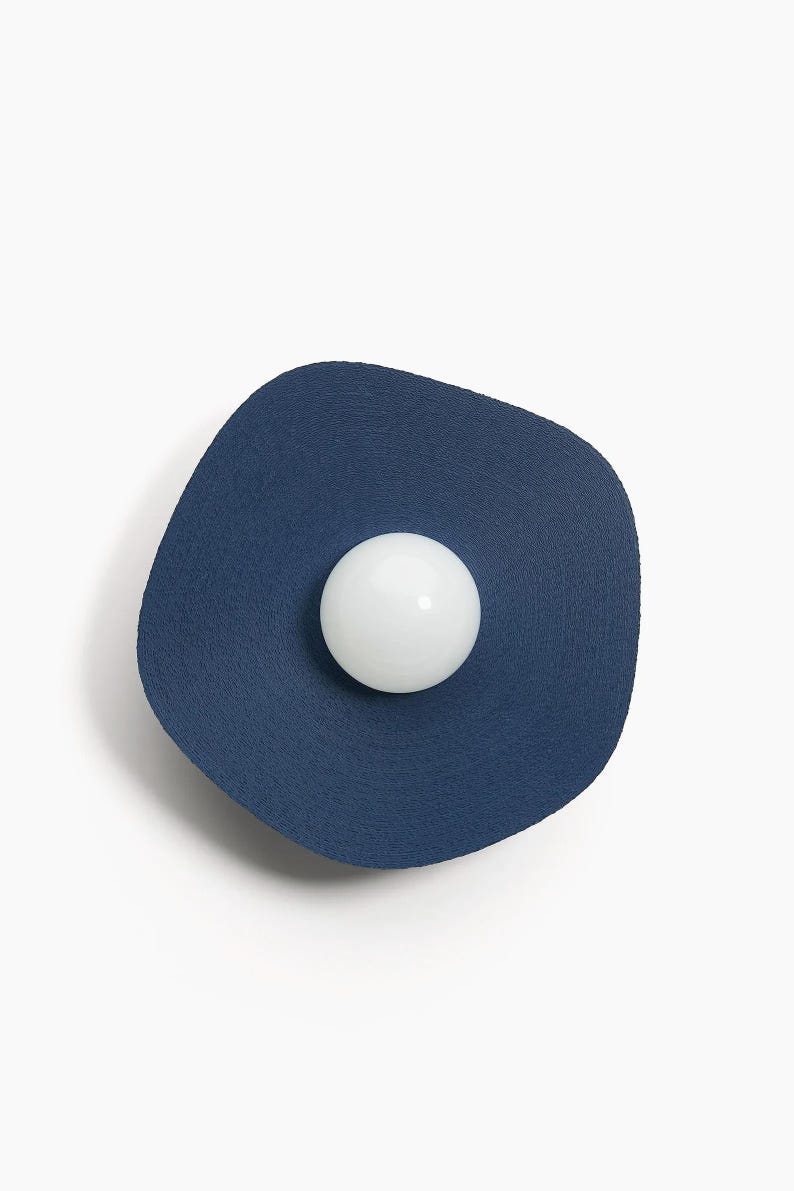 May include: A blue wall sconce with a white round light bulb in the center.
