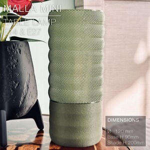 May include: A green table lamp with a textured fabric shade. The lamp is 12 inches in diameter and 20 inches tall. The base is 3.5 inches tall.