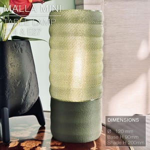 May include: A green table lamp with a textured shade and a base that is 120 mm in diameter. The lamp is 200 mm tall and has a base height of 90 mm. The lamp is labeled "MALLA MINI TABLE LAMP E14 & E27".