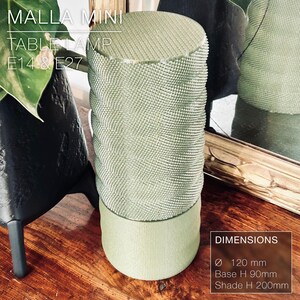 May include: A green table lamp with a textured shade and a base that is 120 mm in diameter. The lamp is labeled "MALLA MINI TABLE LAMP E14 & E27" and has dimensions of 120 mm in diameter, 90 mm base height, and 200 mm shade height.