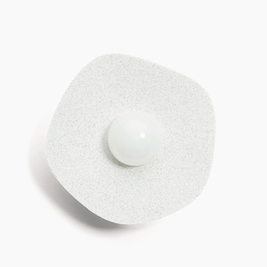 May include: A white, round, speckled, wall-mounted light fixture with a white, round, frosted glass shade.