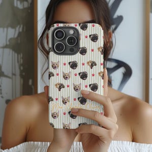 Puede incluir: Una funda de tel&eacute;fono con un patr&oacute;n repetido de caras de gatos y perros, huellas de patas y rayas verticales. La funda tiene una escritura dorada que dice "Max-Charlie-Oliver". La funda se sostiene frente a una persona.