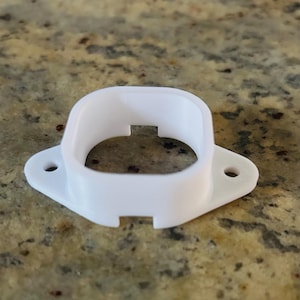May include: White plastic 3D printed part with a square opening and two small holes on the sides.