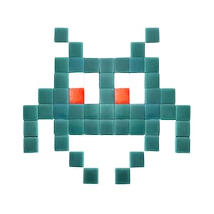 Puede incluir: Una nave espacial extraterrestre pixelada hecha de azulejos cuadrados azul turquesa con ojos rojos. La nave espacial tiene un fondo redondeado y dos brazos.