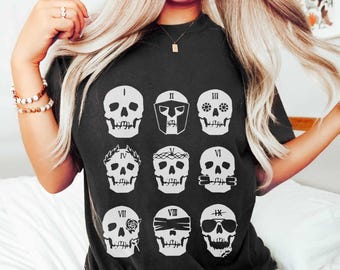 May include: Black t-shirt with a white graphic of nine skulls, each with a different design and Roman numeral. The skulls are arranged in three rows of three.