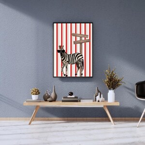 Può includere: Una stampa artistica incorniciata con una zebra con occhiali da sole, in piedi davanti a un cartello stradale. Lo sfondo presenta strisce verticali rosse e bianche. L'opera d'arte è esposta sopra un tavolino di legno.