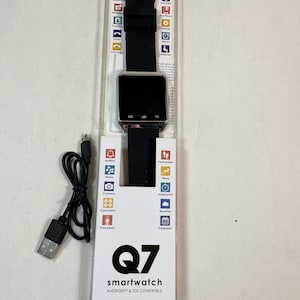 以下が含まれることがあります： 銀色のフレームと黒いバンドが付いた黒いスマートウォッチ。時計は正方形の画面を持ち、通知、音楽、カメラ、電卓、天気、カレンダーなど、さまざまな機能を備えています。時計はAndroidとiOSデバイスに対応しています。時計は、「Q7 smartwatch」というブランド名が印刷された白い箱に梱包されています。