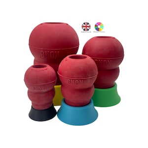 Puede incluir: Una colección de juguetes para perros de goma roja en varios tamaños. Cada juguete tiene una parte superior redondeada con un agujero y una base en diferentes colores, incluyendo negro, azul, amarillo y verde. Los juguetes están etiquetados con la marca "KONG".