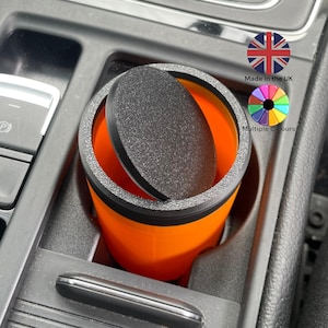 May include: Orange car cup holder with a black lid. The lid has a textured surface. Made in the UK. Multiple colours.
