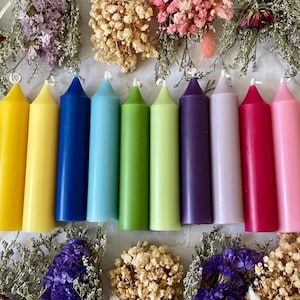 May include: A set of ten candles in various colors, including yellow, light yellow, blue, light blue, green, light green, purple, light purple, red, and pink. The candles are all the same size and shape, with a pointed tip.