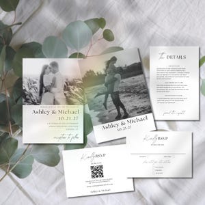 Op de afbeelding: Een verzameling trouwbriefpapier met zwart-witfoto's van een stel. De set bevat uitnodigingen, RSVP-kaarten en detailkaarten. De namen "Ashley & Michael" en de datum "10.21.27" zijn prominent aanwezig.
