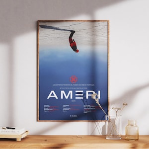 May include: A poster with a blue background and a person in a red and black suit hanging upside down from a ski. The poster has the text "AMER" in white letters and the text "LOS AUTORES TE INVITAN AL PODER DE CREAR PORTALES" in smaller red letters.
