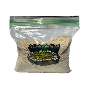 May include: A clear plastic bag filled with light brown material, sealed with a green zipper. A label on the bag features the text "A Circle in the Wood" above an image of mushrooms.