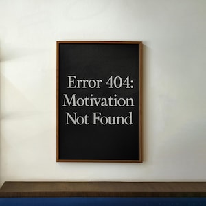 Peut inclure: Un panneau noir encadré de bois brun avec le texte blanc « Error 404: Motivation Not Found ». Le panneau est accroché à un mur blanc.