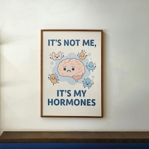 May include: A framed print with a light blue background and a cartoon brain with a sad expression. The text "IT'S NOT ME, IT'S MY HORMONES" is written in blue letters. The brain is surrounded by cartoon organs with angry expressions.