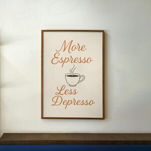 Peut inclure: Une impression encadrée avec le texte "More Espresso Less Depresso" en lettres orange. Une image stylisée d'une tasse de café avec de la vapeur qui s'en échappe est entre les deux lignes de texte.
