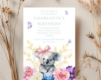 Puede incluir: Una tarjeta de invitación blanca con un koala que lleva un lazo rosa, rodeado de flores rosas, blancas y moradas. El texto de la tarjeta dice "Por favor, únase a nosotros para celebrar el cumpleaños de Charlotte, 19 Evergreen Way, West Pennant Hills, sábado 15 de abril a las 12:00 PM, RSVP: Ava al 0400 000 000 antes del 7 de mayo."