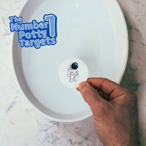 May include: A white sticker with a cartoon astronaut in a white spacesuit with a blue visor. The sticker is being held over a white bowl with water.