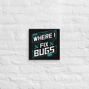 Może przedstawiać: Kwadratowy czarny obraz na płótnie z napisem "WHERE I FIX BUGS" w kolorze białym i turkusowym. Projekt zawiera grafiki kluczy i błędów. Płótno jest zamontowane na białej ceglanej ścianie.