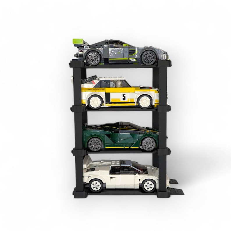 Puede incluir: Un expositor de coches de metal negro con cuatro niveles. El expositor contiene cuatro coches en miniatura diferentes: un coche verde, un coche blanco con una franja amarilla y el n&uacute;mero 5, un coche blanco con una franja verde y un coche gris con una franja verde.