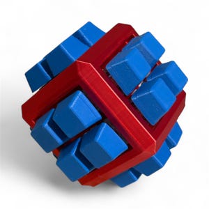 Puede incluir: Un cubo de rompecabezas 3D rojo y azul. El cubo tiene un marco exterior rojo con piezas azules en forma de cubo insertadas. El rompecabezas está diseñado para resolverse manipulando las piezas azules dentro del marco rojo. Un rompecabezas.