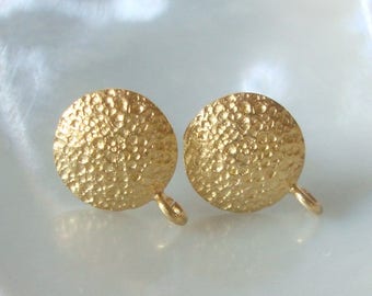 May include: A pair of gold-toned earrings with a textured, hammered finish. The earrings are round and have a simple, minimalist design.