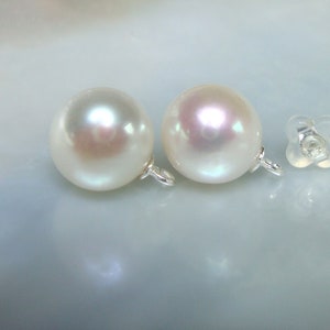 May include: Two white pearl earrings with silver clasps and two clear plastic earring backs.