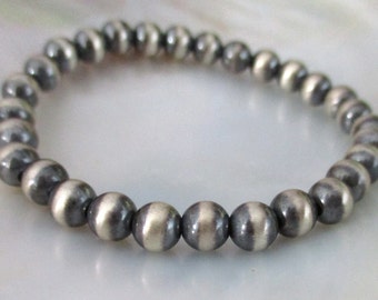 May include: A silver bracelet with black and white striped beads.