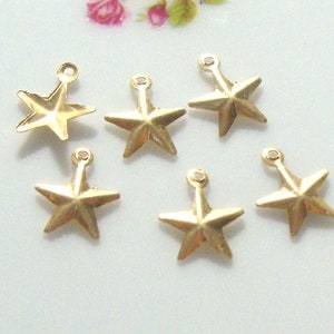 Può includere: Sei ciondoli a forma di stella in metallo dorato con un anello in cima. Le stelle hanno un design a cinque punte con una superficie testurizzata.