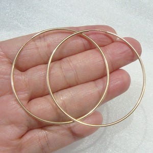 May include: A pair of gold hoop earrings. The hoops are thin and circular.