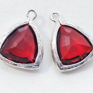 Peut inclure: Deux pendentifs en argent de forme triangulaire avec des accents de cristal rouge.