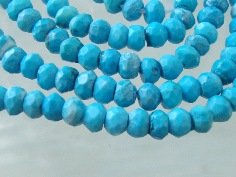 May include: A strand of turquoise beads, each bead is faceted and has a light blue color.