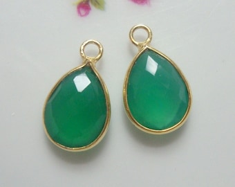 May include: Two gold-plated teardrop-shaped pendants with green gemstone inserts.