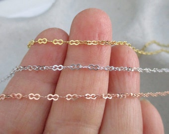 May include: Three delicate chains in gold, silver, and rose gold. Each chain is made of small, linked ovals.