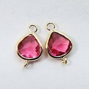 Puede incluir: Dos abalorios de forma de lágrima de color dorado con detalles de cristal rosa. Cada abalorio tiene un bucle en la parte superior para sujetarlo a joyas.