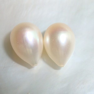 May include: Two pearlescent white teardrop-shaped pearls.