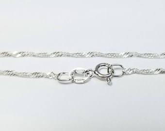 May include: A silver chain necklace with a lobster clasp fastening. The chain is a delicate, twisted design.