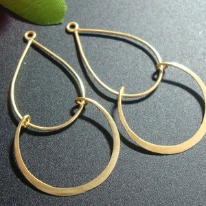 May include: A pair of gold-toned earrings with a teardrop shape and a smaller circle attached to the bottom.