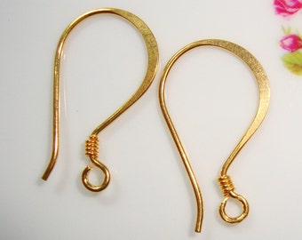 May include: A pair of gold-toned earring hooks. The hooks are made of metal and have a smooth, slightly curved shape. They are designed to be used with other jewelry components.