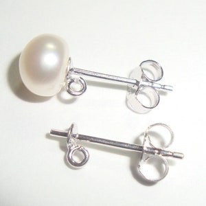 May include: A pair of silver stud earrings with a white pearl on each earring.