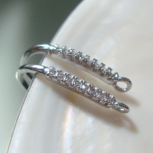May include: Two silver-toned jewelry clasps with a row of clear rhinestones on each.