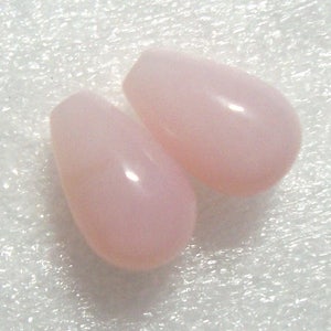 May include: Two teardrop-shaped pink opal beads. The beads are smooth and have a glossy finish.