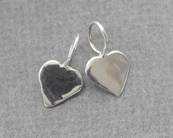 May include: Two silver heart-shaped earring charms with a loop at the top for attaching to jewelry.